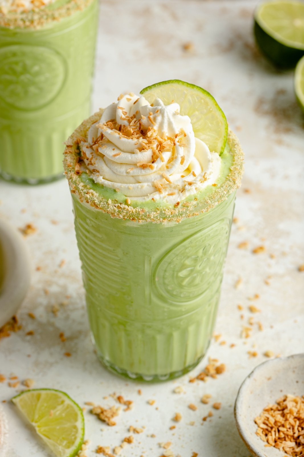 El Batido cremoso de tarta de lima y coco está hecho con ingredientes simples y un delicioso sabor a coco. Esta increíble receta de Batido de tarta de lima sabe como una rebanada de su postre favorito, ¡pero está repleta de proteínas y vegetales furtivos! Disfrute del desayuno, merienda o incluso un postre saludable. Batido de tarta de lima en un vaso con crema batida encima