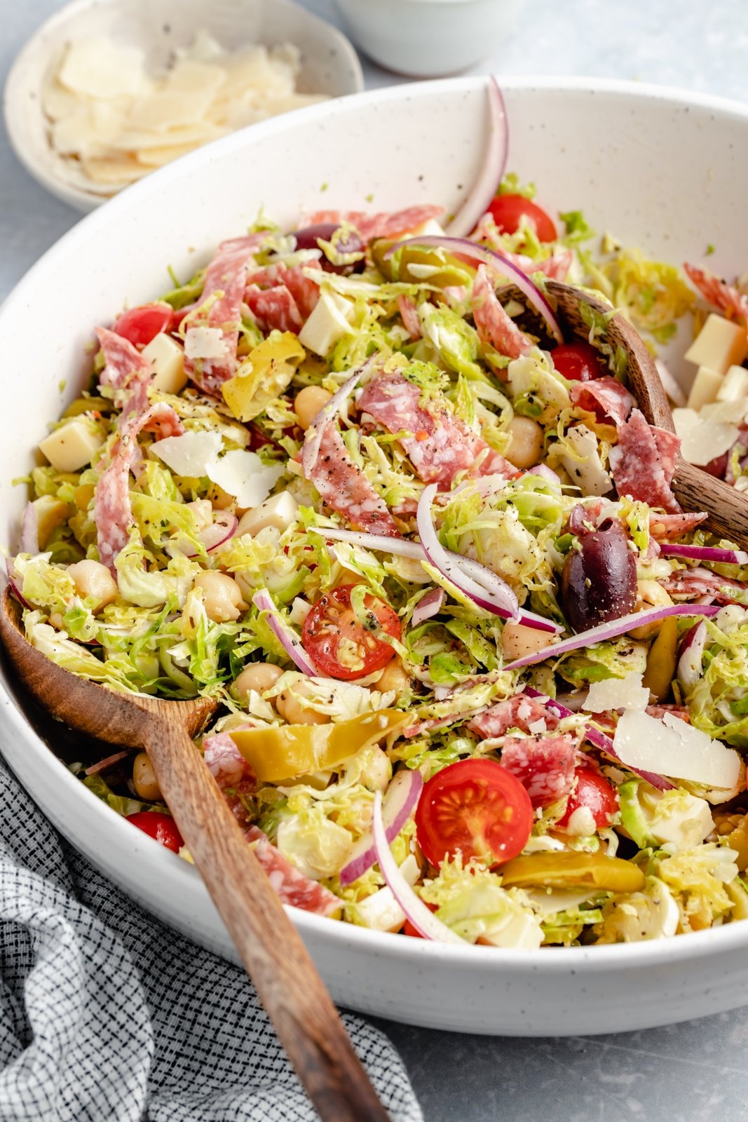 Magnífica receta de ensalada picada italiana con coles de Bruselas ralladas, garbanzos, verduras, salami, aceitunas, pepperoni y delicioso queso. ¡Esta deliciosa y fácil ensalada italiana de coles de Bruselas picadas con un ligero aderezo italiano es el almuerzo perfecto o una cena fresca! Ensalada italiana de coles de Bruselas picadas en un bol
