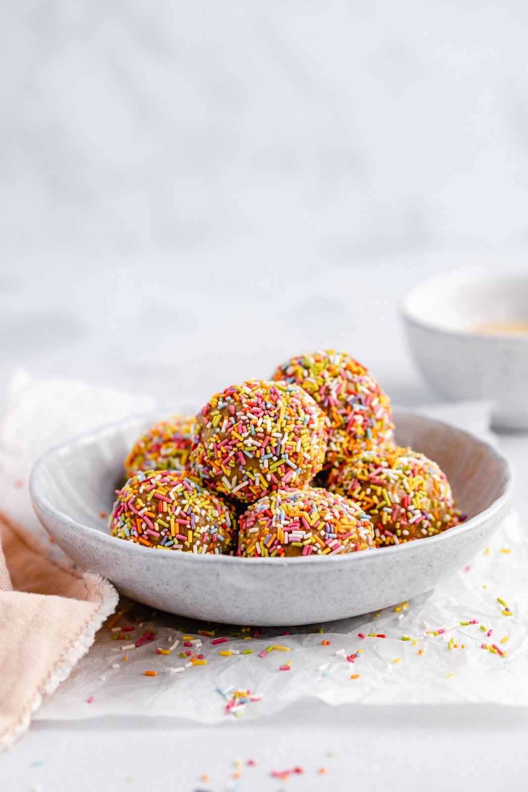 ¡No hornee picaduras de energía de masa de galleta de pastel de cumpleaños que saben igual que la masa de pastel! Hechos con siete ingredientes simples, estos refrigerios veganos energéticos fáciles de pastel de cumpleaños están endulzados naturalmente con jarabe de arce puro y rellenos con chispas festivas. ¡El tentempié o tentempié repleto de proteínas perfecto! Pastel de cumpleaños saludable Bocaditos de energía en un tazón