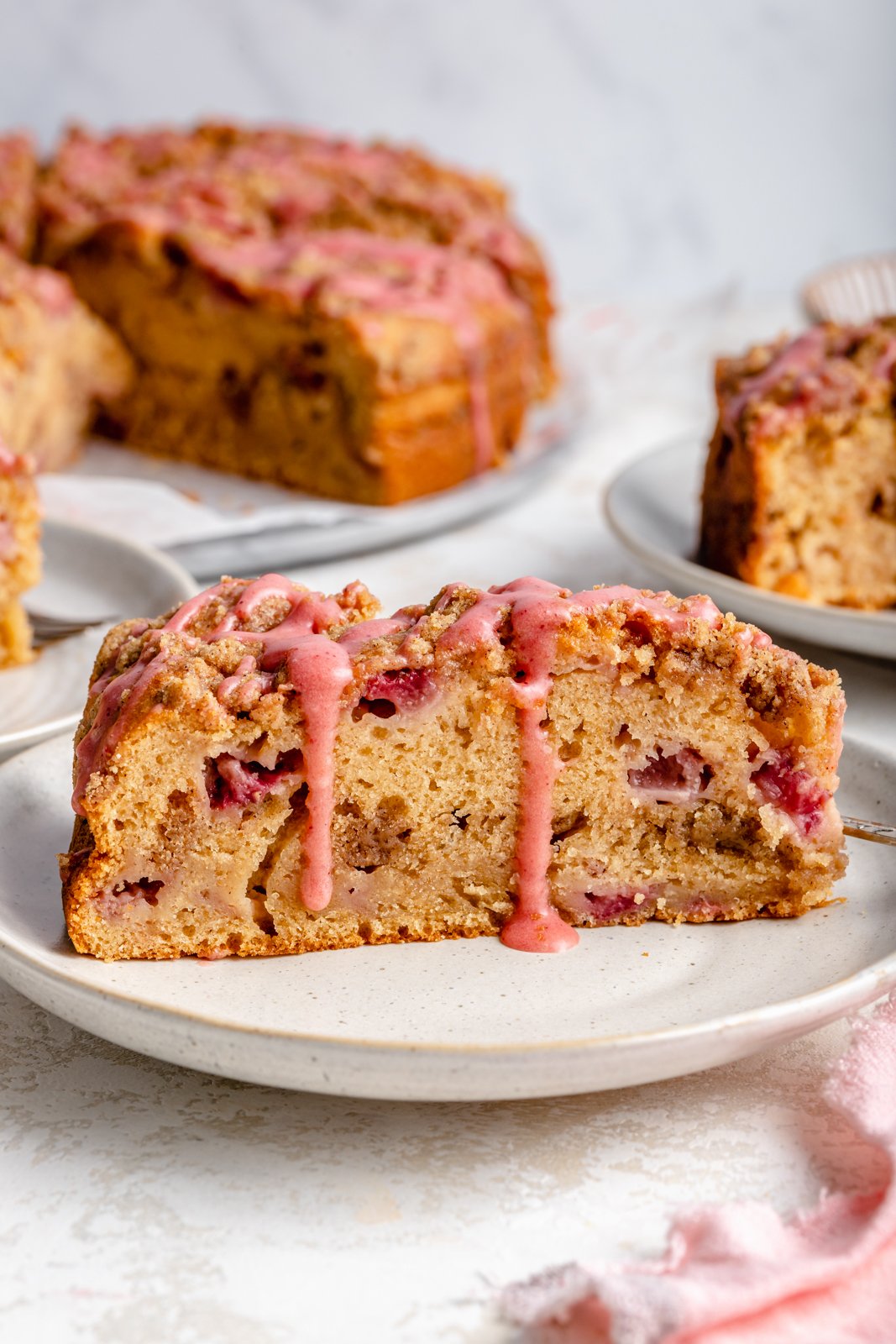 Hermoso pastel de café con fresas hecho con rica mantequilla marrón y cubierto con un encantador glaseado de fresas. Esta maravillosa receta de pastel de café con fresas es jugosa y deliciosa con la cobertura perfecta para desmoronarse. ¡El mejor método para quedarse sin fresas frescas durante todo el verano! Rebanadas de pastel de café de fresa con glaseado de fresa en un plato