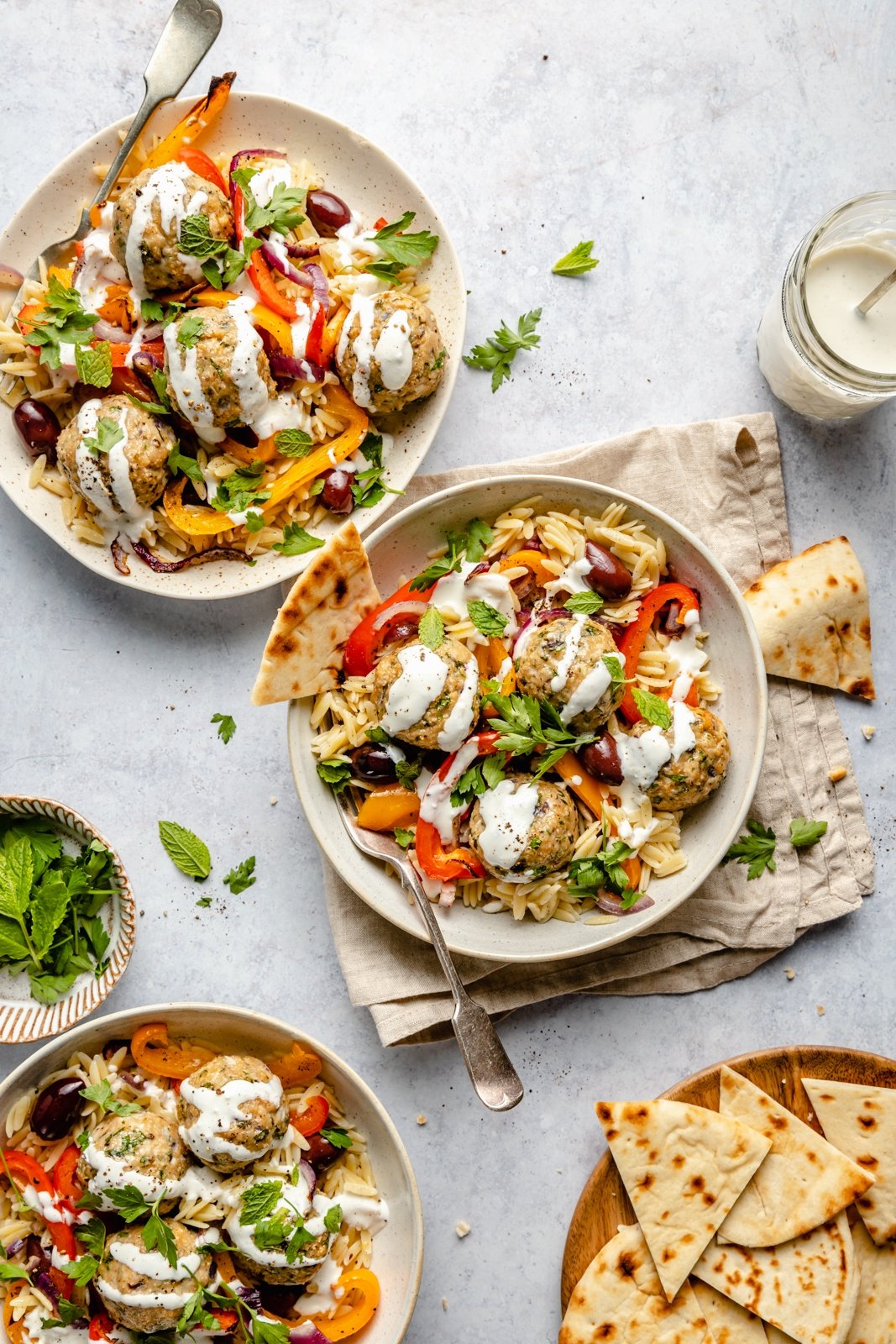Deliciosas albóndigas de pavo griego con orzo de limón, verduras tiernas y salsa cremosa de queso feta. ¡Rellenas con un montón de hierbas maravillosas, estas saludables albóndigas de pavo griego asado son la comida perfecta para la noche entre semana! Tres tazones de albóndigas de pavo griegas saludables con orzo