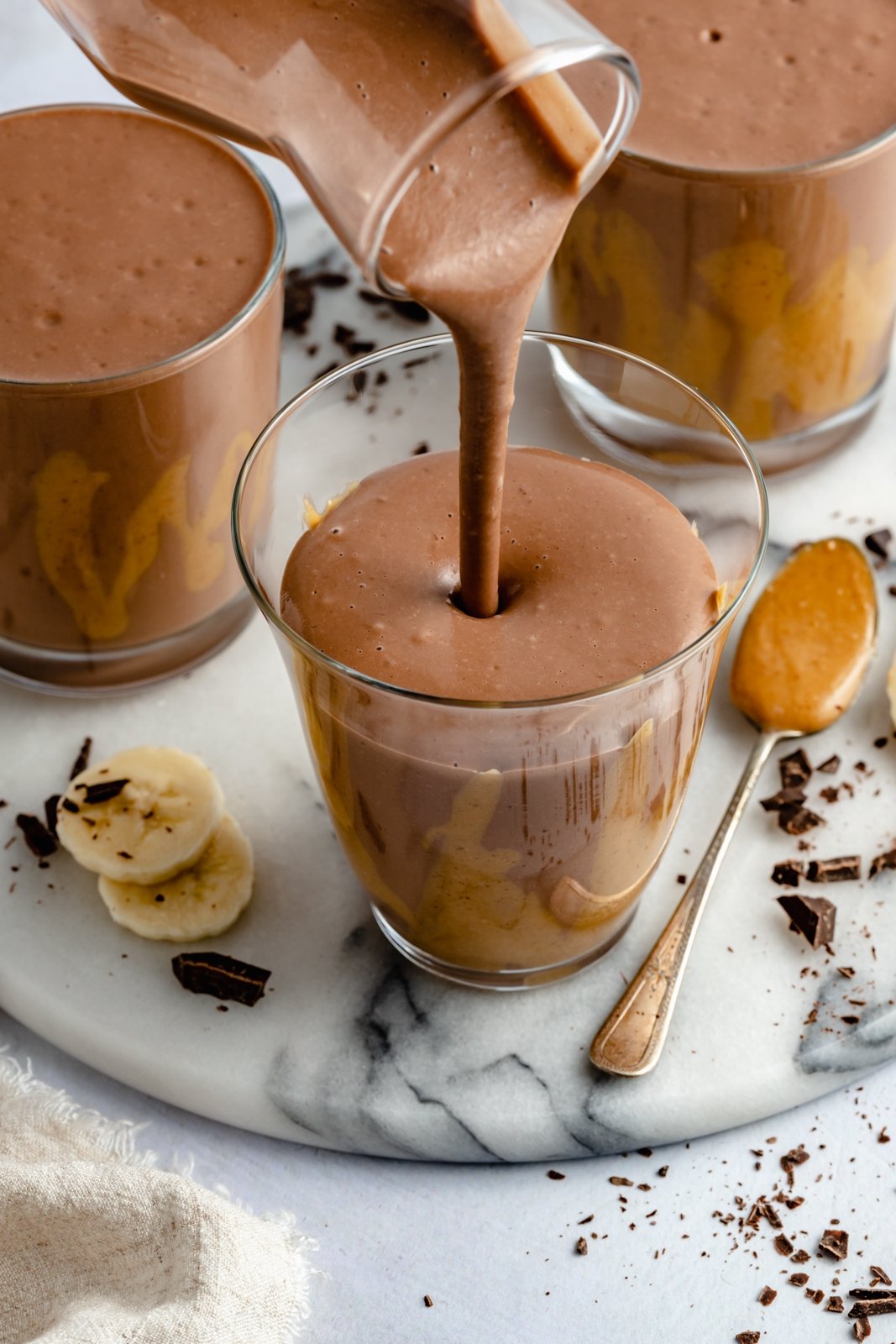 ¡Delicioso batido cremoso de chocolate con mantequilla de maní y plátano que sabe como el batido de Wendy's! Esta receta saludable de licuado de plátano y chocolate está hecha con solo cinco ingredientes y es fácil de personalizar con su potenciador nutricional favorito. ¡Perfecto para el desayuno, la merienda o incluso el postre! Vierta un saludable batido de chocolate y plátano en un vaso