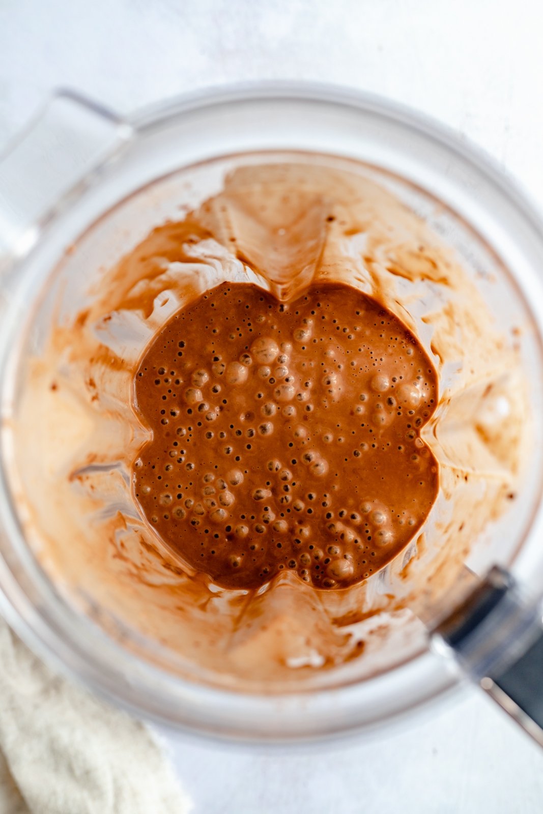 ¡Un delicioso batido cremoso de chocolate con mantequilla de maní y plátano que realmente sabe como el batido de Wendy's! Esta saludable receta de batido de chocolate y plátano está hecha con solo cinco ingredientes y es fácil de usar con su refuerzo nutricional favorito Personalizado. Perfecto para el desayuno, la merienda o incluso el postre ! Vista superior del batido de plátano con mantequilla de maní y chocolate en la licuadora