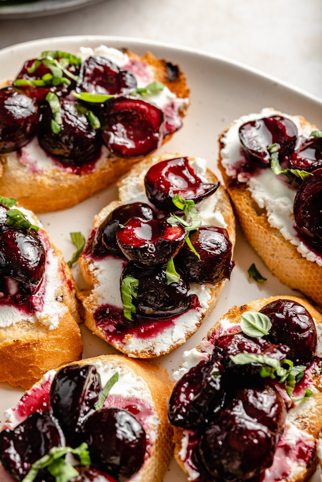Solo necesitas un puñado de ingredientes y en menos de una hora puedes preparar estos hermosos crostinis asados con jugosas cerezas asadas, queso de cabra cremoso y picante y albahaca fresca. Estas sencillas y deliciosas recetas de crostini asados son el aperitivo perfecto para el verano fiestas o en cualquier momento que te estés divirtiendo! Crostini asado con cereza asada y queso de cabra en un plato