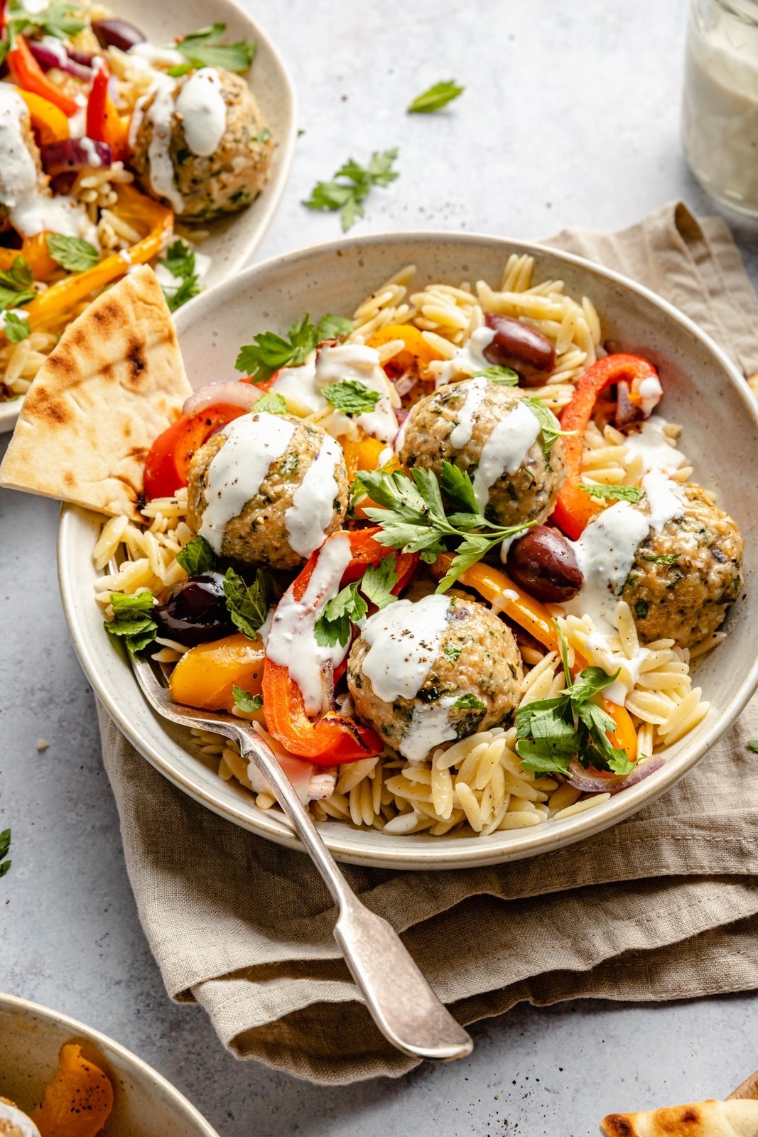 Deliciosas albóndigas de pavo griego con orzo de limón, verduras tiernas y salsa cremosa de queso feta. ¡Rellenas con un montón de hierbas maravillosas, estas saludables albóndigas de pavo griego asado son la comida perfecta para la noche entre semana! Albóndigas de pavo griego con salsa orzo y queso feta en un bol