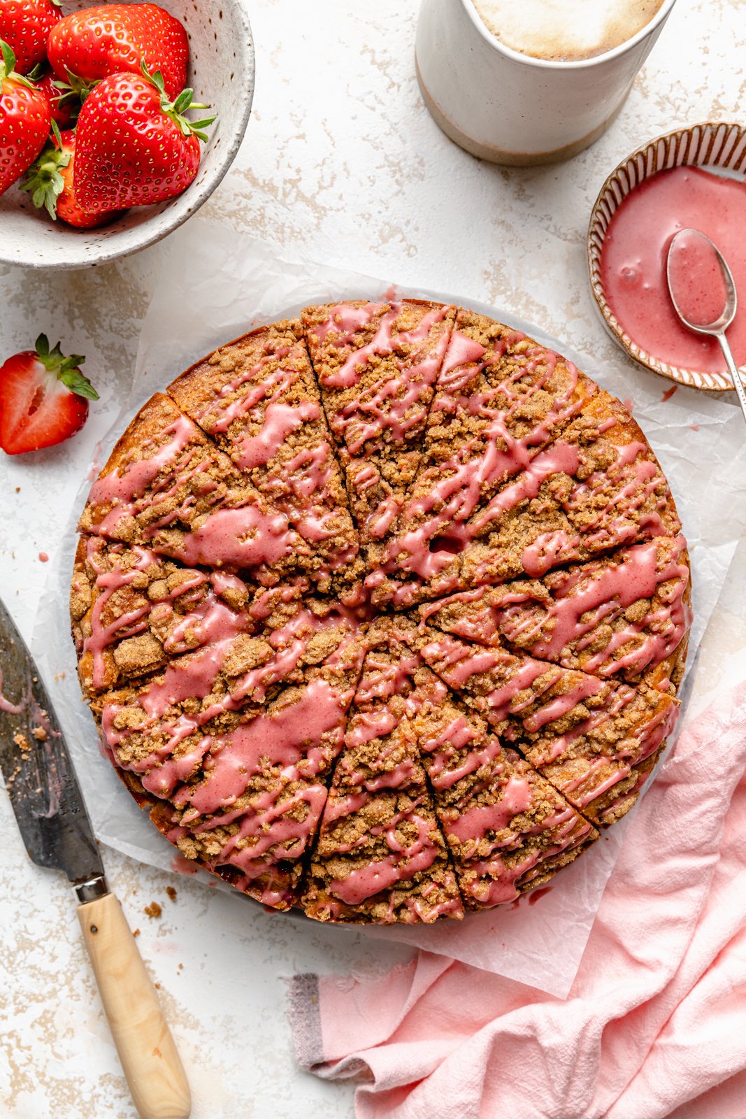 Un hermoso pastel de café con fresas hecho con rica mantequilla marrón y cubierto con un hermoso glaseado de fresas. Esta maravillosa receta de pastel de café con fresas es deliciosa con la miga perfecta encima. ¡La mejor manera de usar fresas frescas durante todo el verano! Pastel de café con fresas en rodajas en pergamino