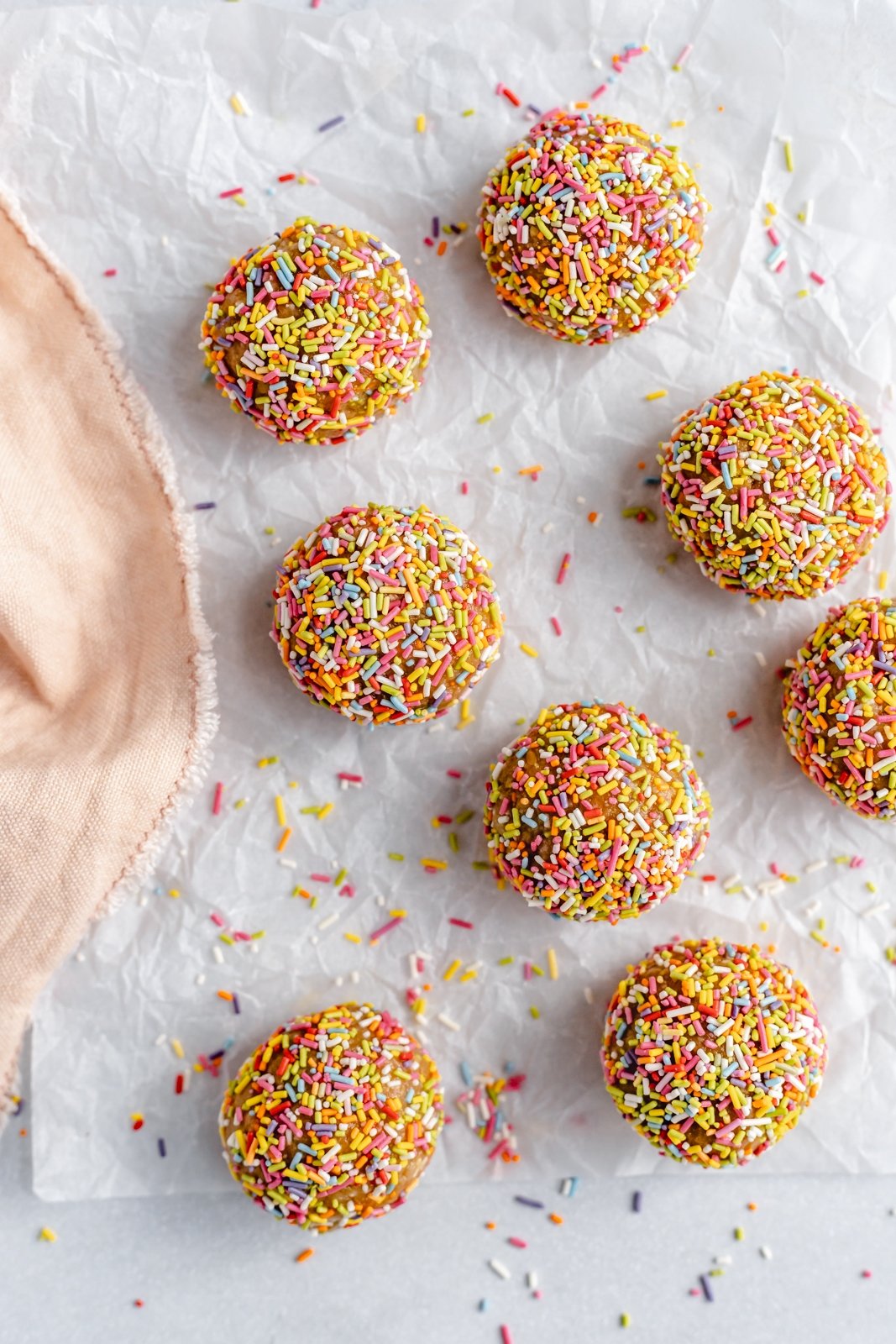 ¡No hornee picaduras de energía de masa de galleta de pastel de cumpleaños que saben igual que la masa de pastel! Hechos con siete ingredientes simples, estos refrigerios veganos energéticos fáciles de pastel de cumpleaños están endulzados naturalmente con jarabe de arce puro y rellenos con chispas festivas. ¡El tentempié o tentempié repleto de proteínas perfecto! Don't Baking Birthday Cake Energy Bites en pergamino