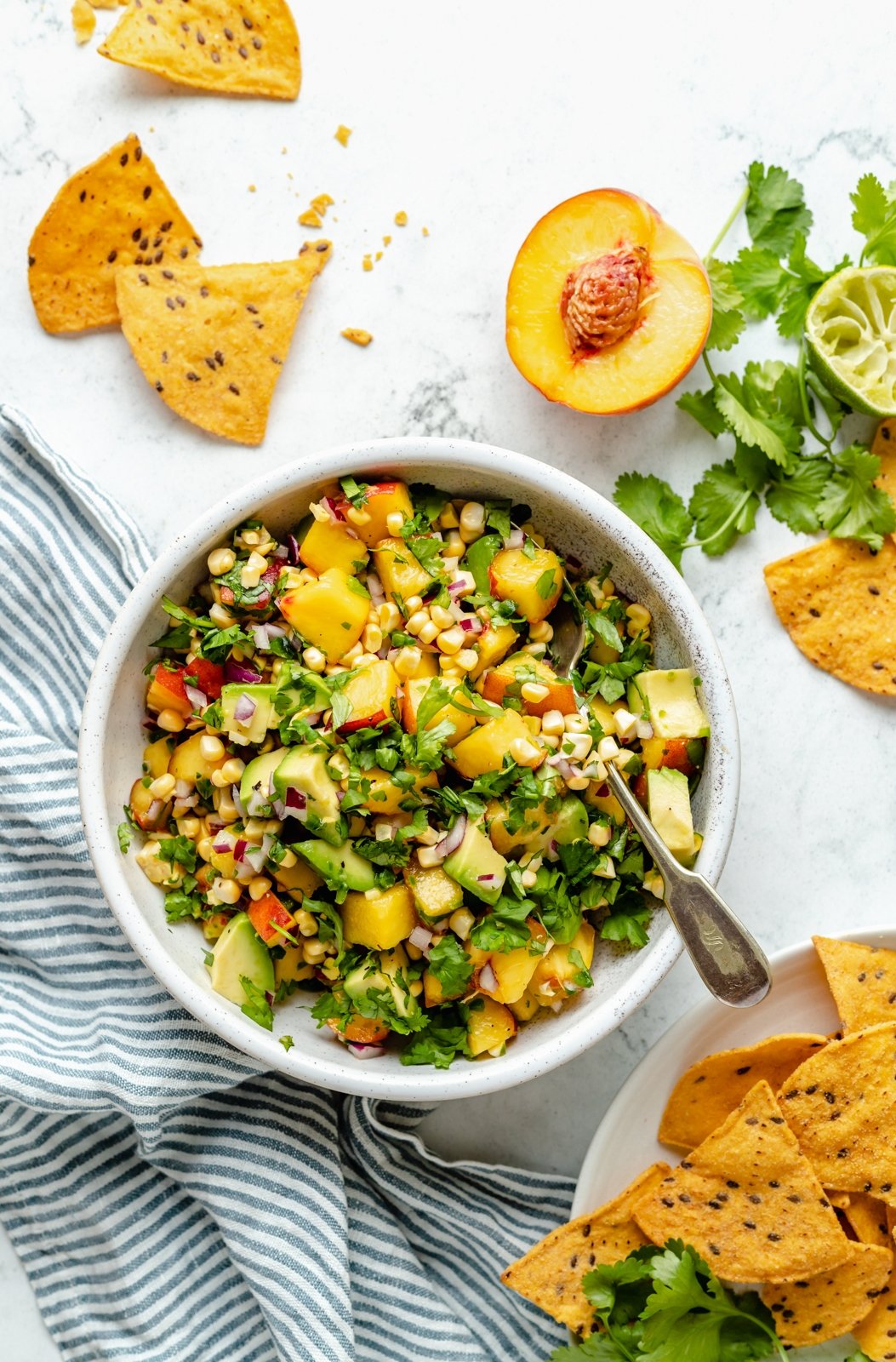 La hermosa salsa de durazno y aguacate está hecha con el calor de duraznos frescos y jugosos, aguacate cremoso, maíz dulce y jalapeños. ¡Esta brillante y deliciosa receta de salsa de durazno es deliciosa con tu rebanada de maíz favorita o sírvela con salmón, tacos de pescado y más! Ensalada saludable de aguacate, melocotón en un plato siguiente a eso por papas fritas
