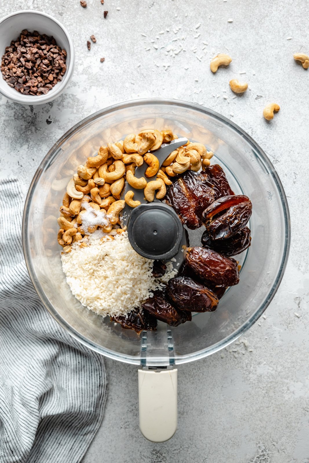 ¡Simples y deliciosas fichas energéticas de anacardo de coco con caramelo salado repletas de proteínas y grasas saludables! Estas fichas energéticas de anacardo de coco no contienen gluten, cereales, son veganas y están endulzadas de forma natural con dátiles Medjool. Directamente del frigorífico o del congelador para una ¡refrigerio saludable o desayuno para llevar! Bocados energéticos de marañón en un procesador de alimentos con ingredientes de coco