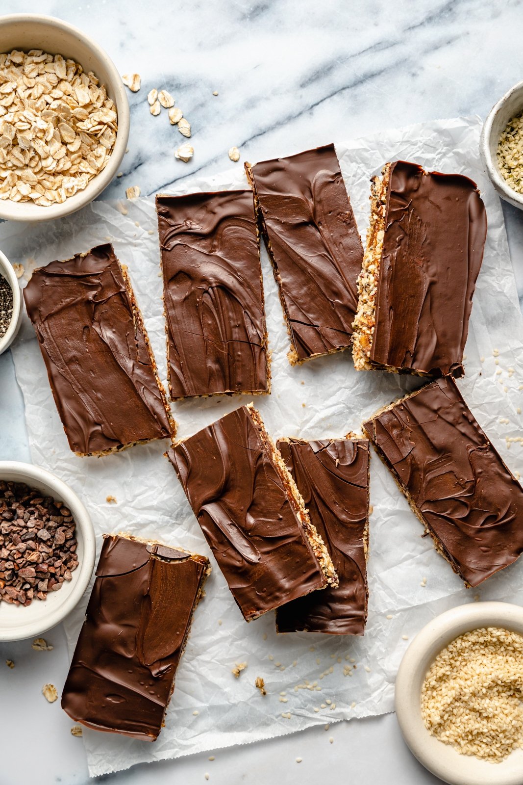 Barras nutritivas de avena con tahini rellenas con semillas de chía, semillas de cáñamo y copos de avena, endulzadas de forma natural con higos secos y miel. Estas sencillas barritas sin hornear están cargadas de fibra y proteína para mantenerte lleno y satisfecho. Rocía con un delicioso chocolate y ¡disfruta de la merienda perfecta o delicia recién sacada de la nevera!” src= Barras de avena Tahini en papel pergamino