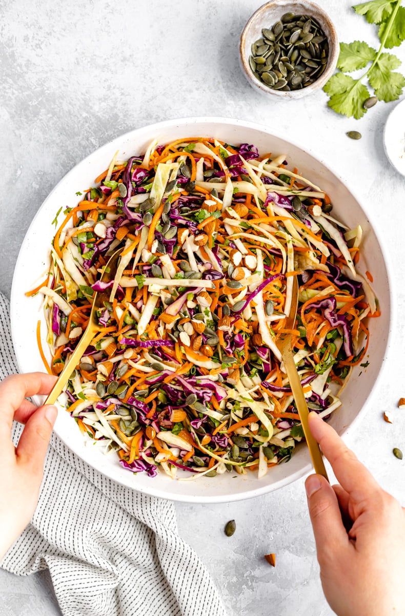 La MEJOR ensalada de col rizada hecha con col rizada morada fresca, zanahorias, cilantro y el picante de los jalapeños. Sin mayonesa ni azúcar, solo un aderezo naturalmente dulce y ligeramente picante con un toque de jarabe de arce puro. Esta es una receta vegana fácil y saludable ¡La receta de ensalada de col rizada no contiene paleo ni lácteos y es perfecta para sus recetas favoritas a la parrilla durante todo el verano! src= ensalada de col saludable mezclada en un tazón con dos cucharas