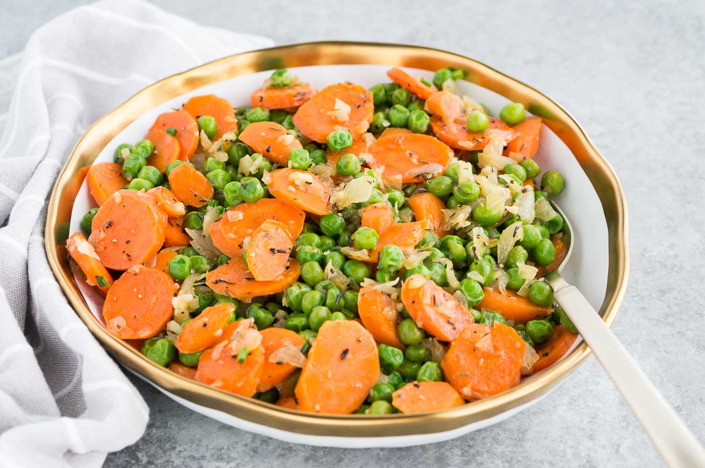 sauteed carrots, peas and onions in a serving bowl