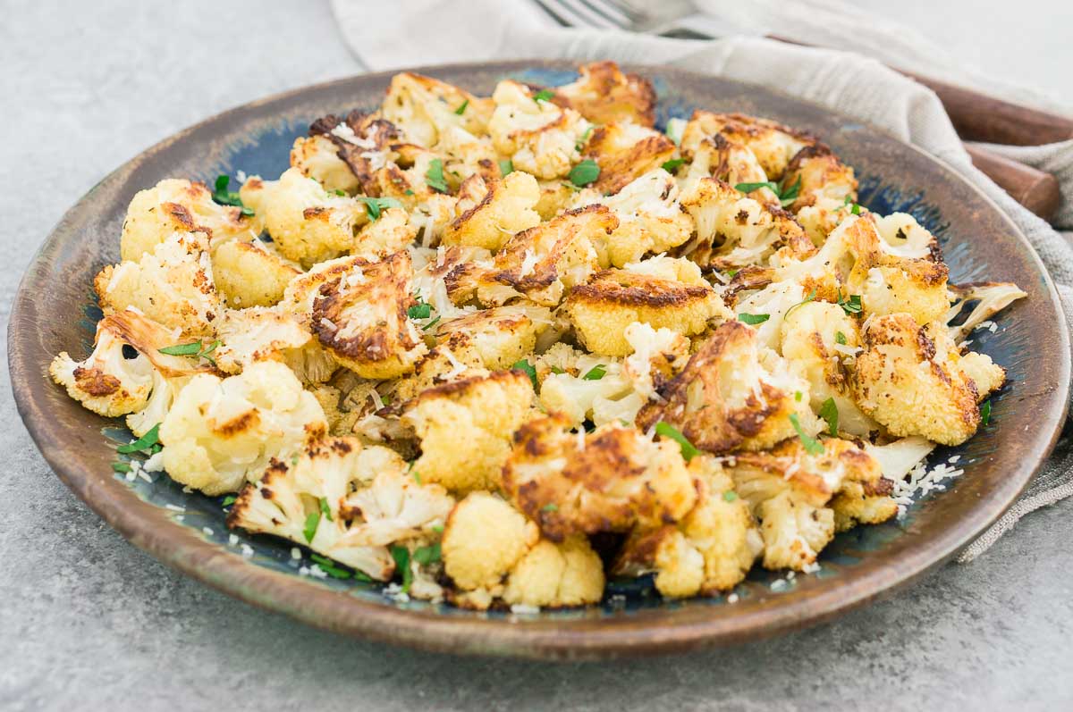roasted garlic cauliflower with grated Parmesan and crispy edges in a plate