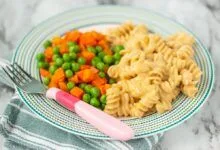 homemade mac and cheese with peas and carrots on a plate