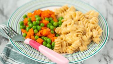 homemade mac and cheese with peas and carrots on a plate