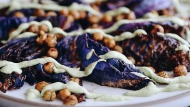 A horizontal picture of roasted cabbage steaks with crispy chickpeas and a cashew-based creamy herb sauce