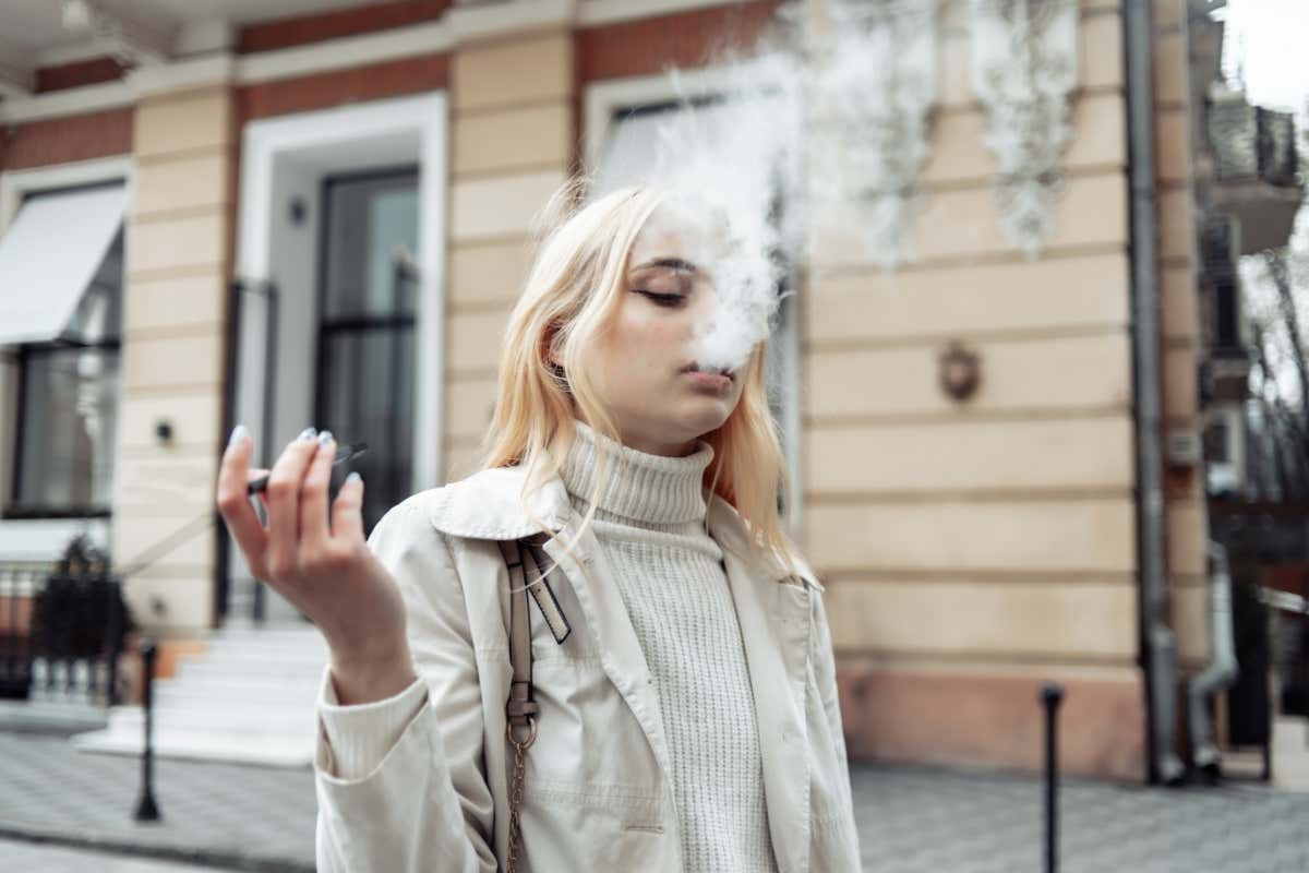 mujer joven fumando un cigarrillo electrónico