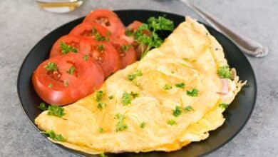 American style omelet on a plate with tomato slices