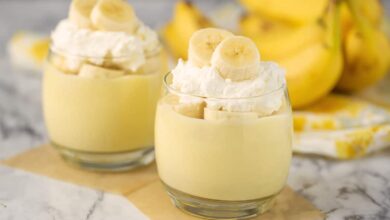 banana pudding in glasses with fresh bananas, whip cream and bananas in the background