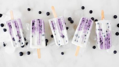 Group of blueberry popsicles. Above view in a row on a white marble background.