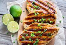 grilled chicken breast with coconut and lime on a wooden cutting board with lime slices