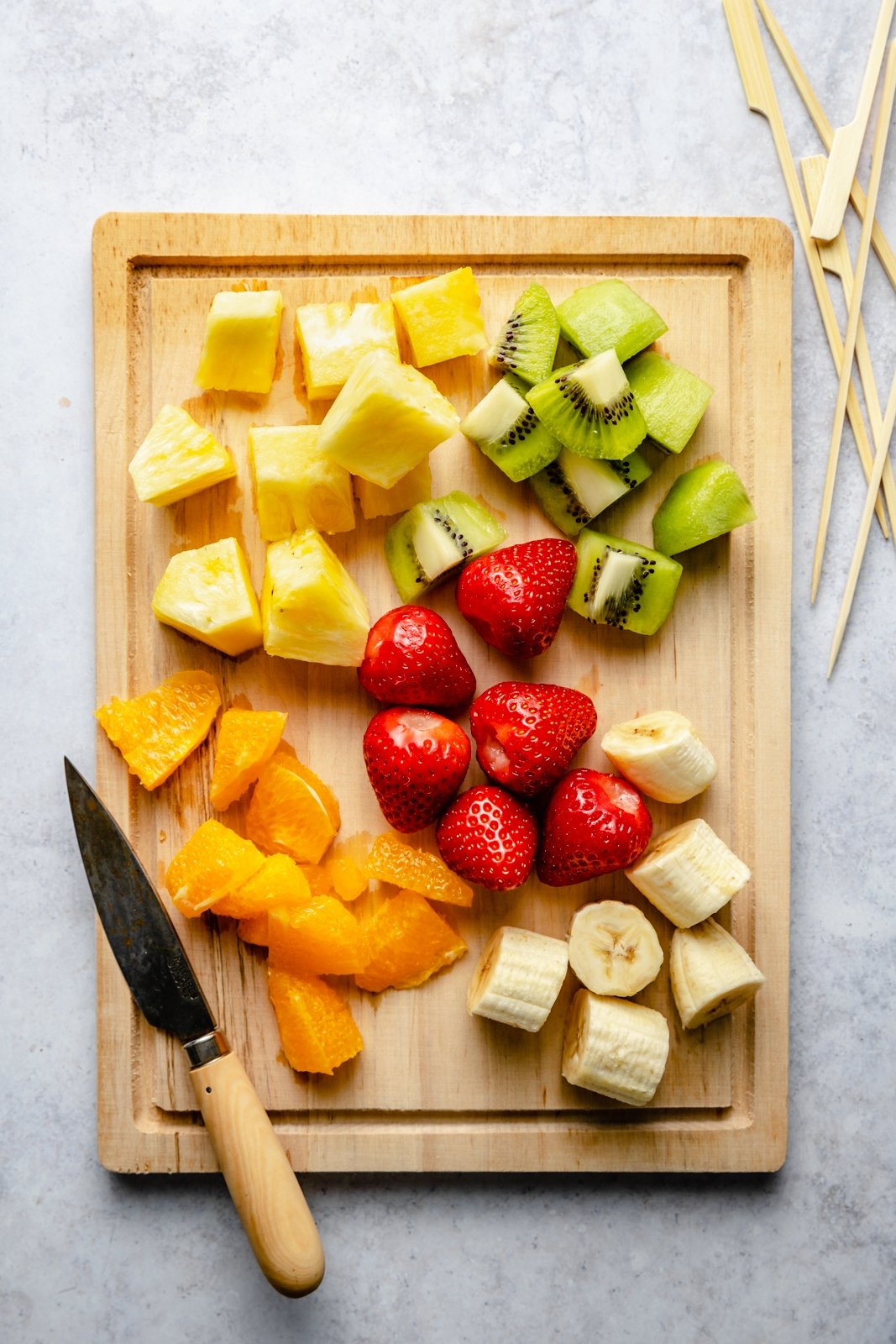 Fruta arcoíris para brochetas de frutas en una tabla para cortar