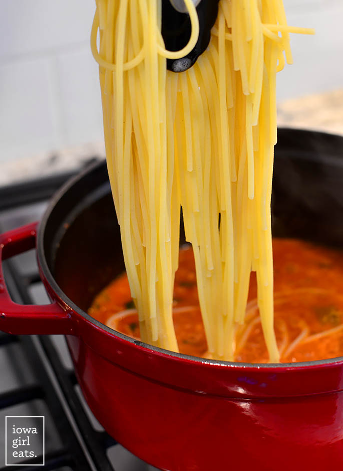 Agregue pasta cocida a una olla de salsa de tomate.