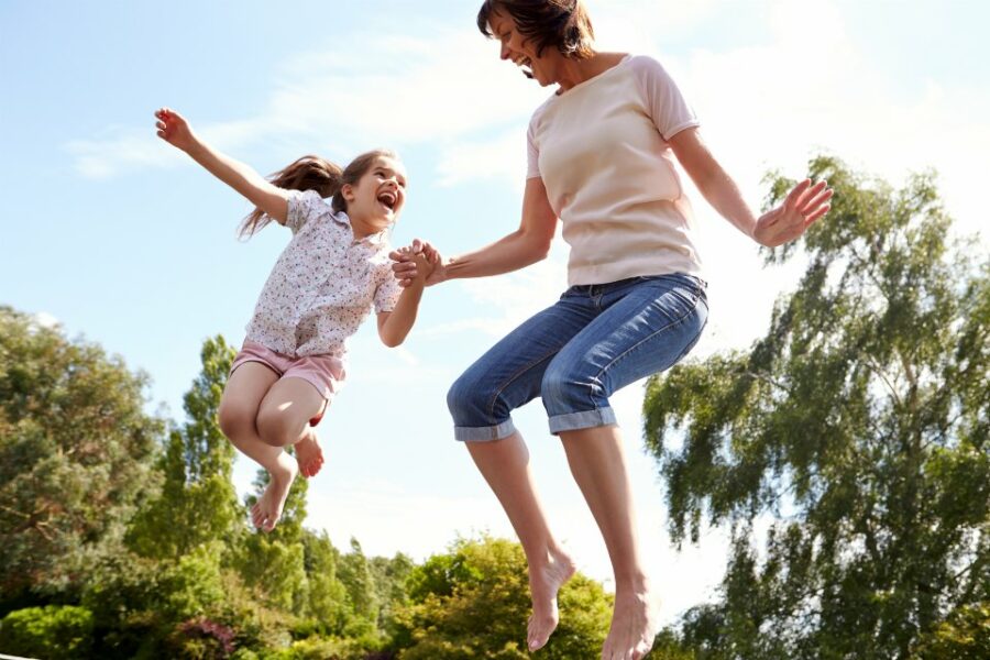 Madre e hija saltando juntas en trampolín