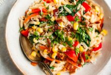 garlic parmesan orzo pasta in a bowl with veggies and a spoon
