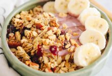 pink smoothie bowl with bananas, granola and honey.