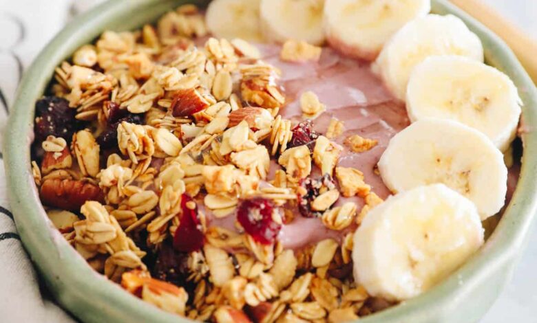 pink smoothie bowl with bananas, granola and honey.