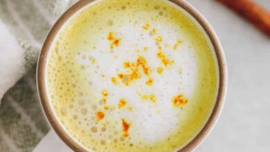 overhead image of a turmeric latte in a white and brown mug.