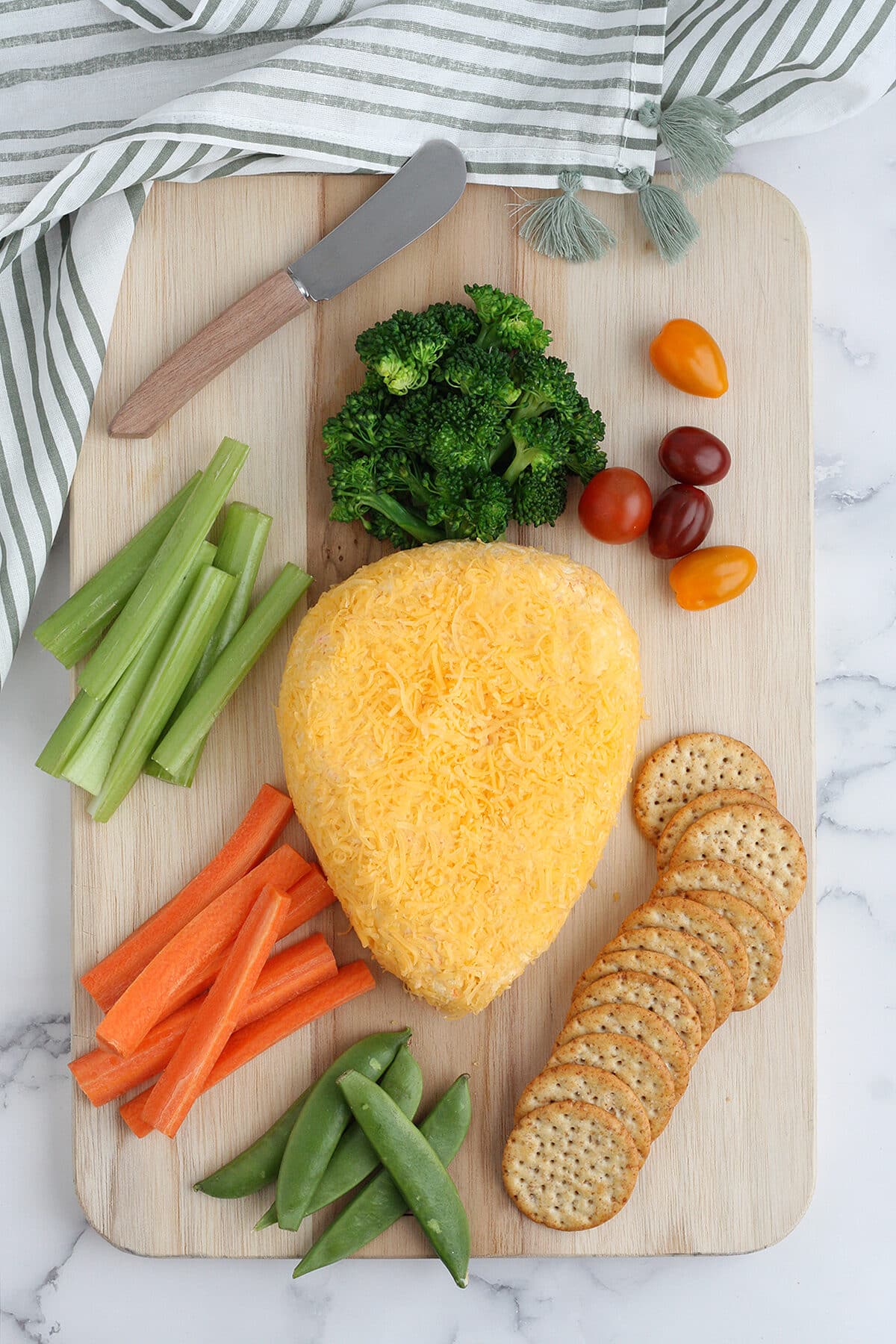 bola de queso en forma de zanahoria con galletas saladas y verduras