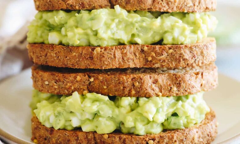 avocado egg salad on two sandwiches stacked on top of one another.