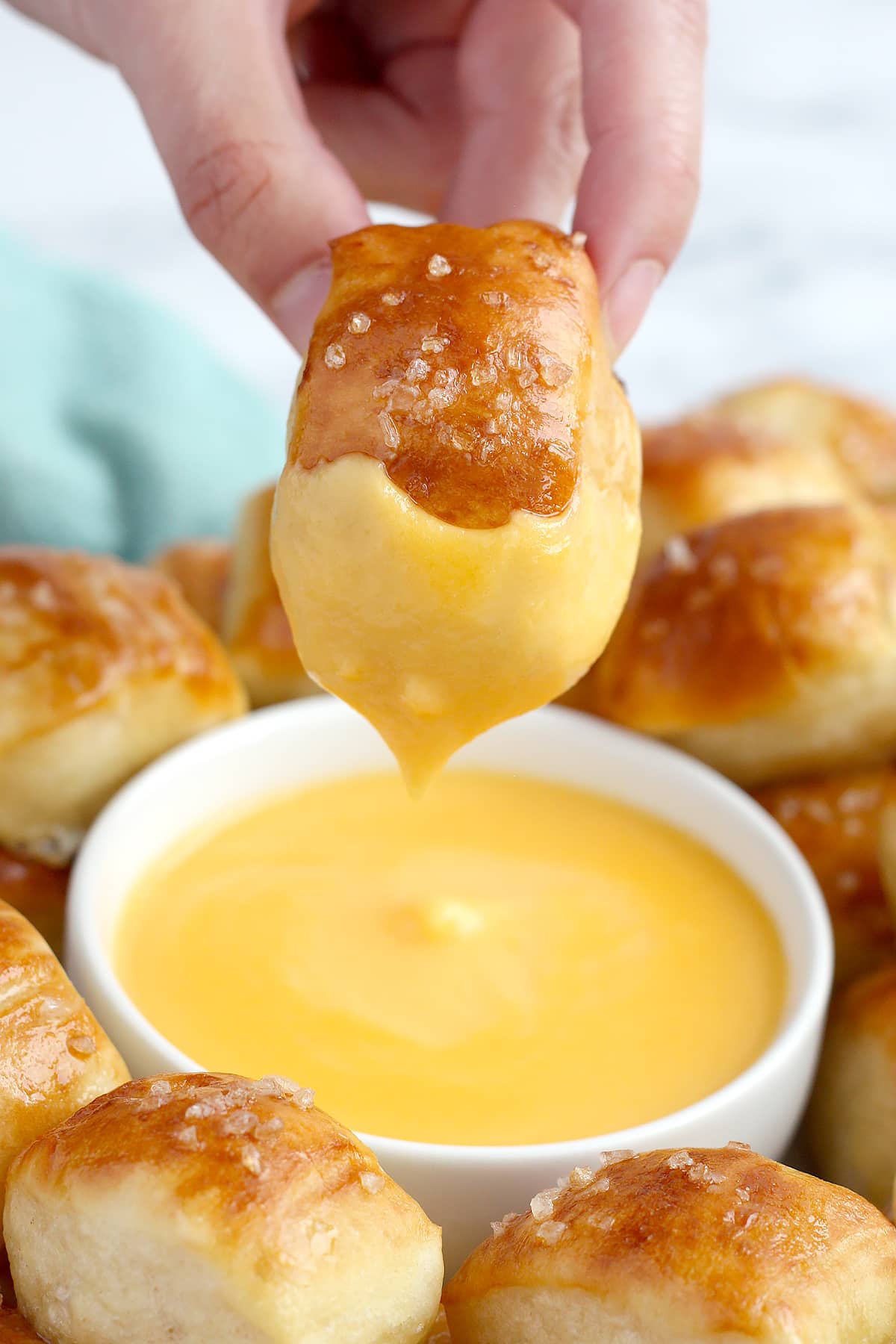 Un trozo suave de pretzel sumergido en un tazón de salsa de queso.